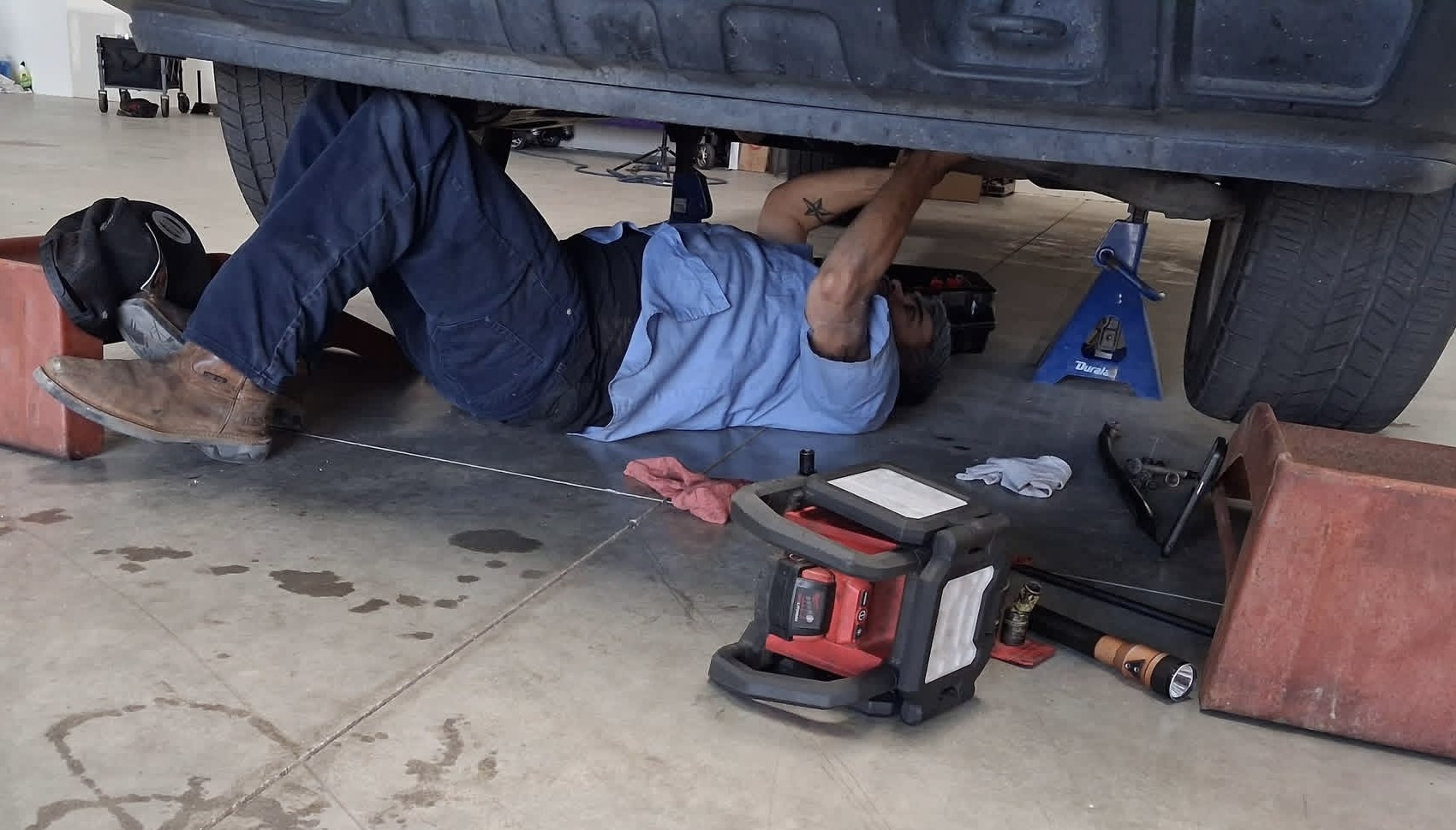 Alex Garza working under a car at Brothers Garage in Bakersfield, CA